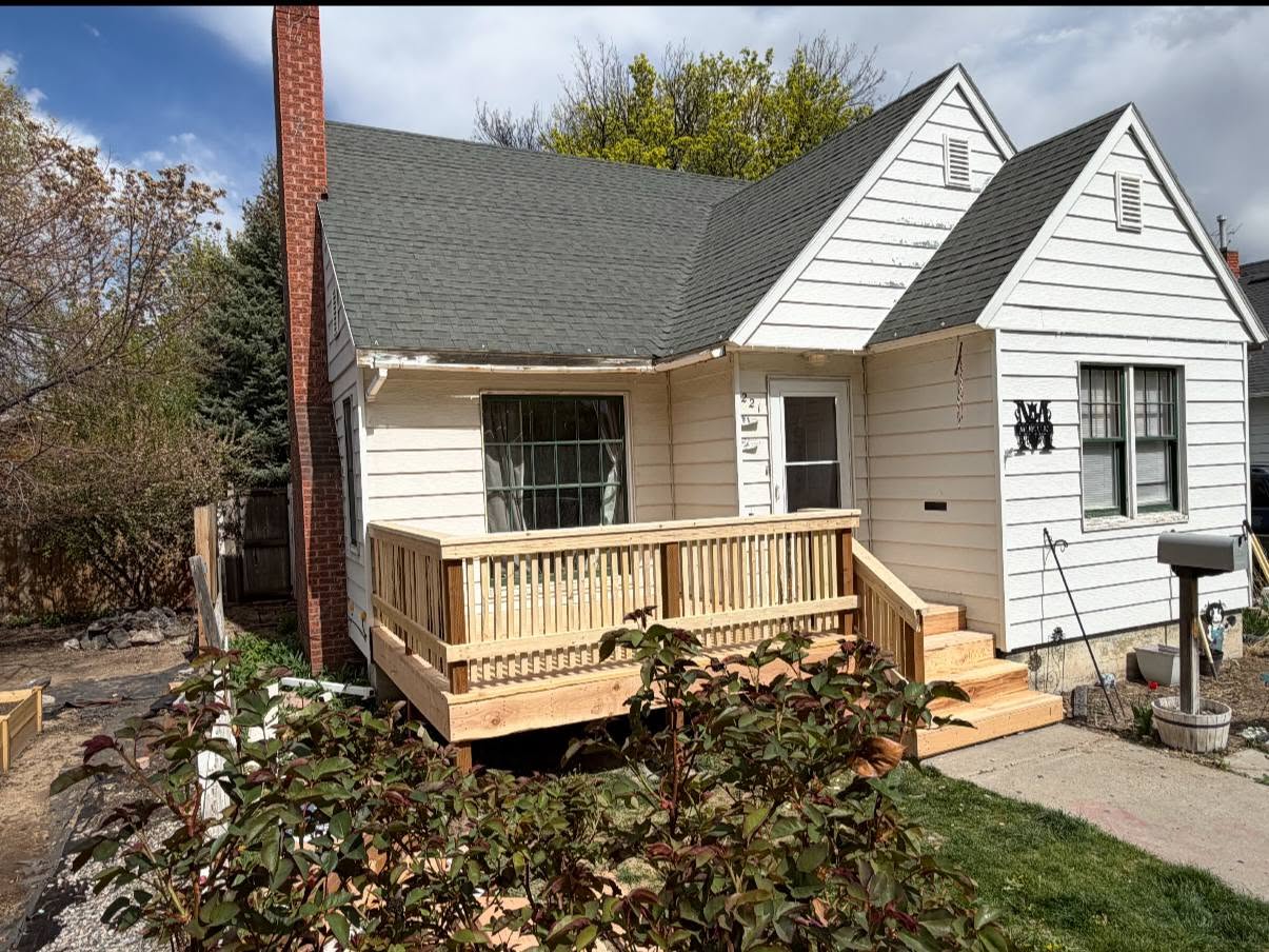 White home with a new light-wood front deck, railings and stairs